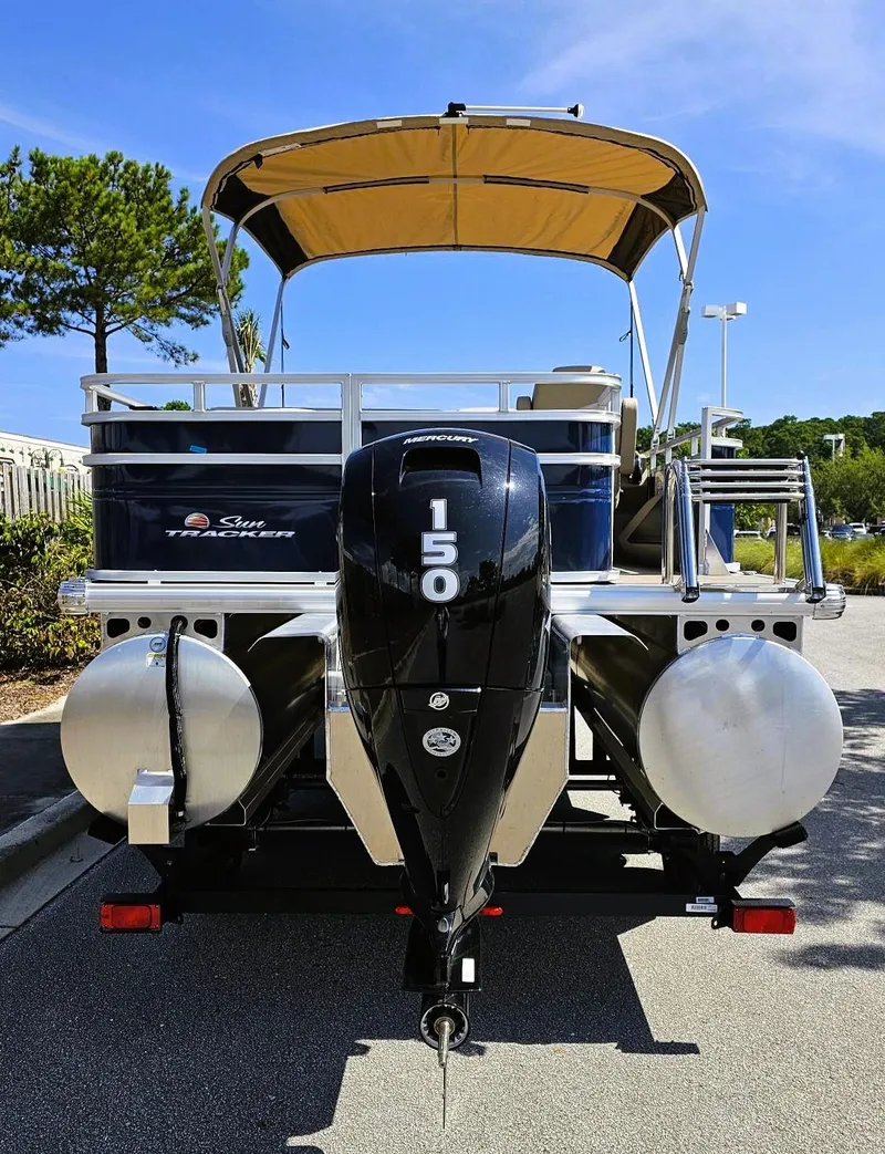 Slide: The Image of 2025 Sun Tracker Fishin' Barge 22 XP3 pontoon boat with 150 HP engine, parked outdoors. - 3