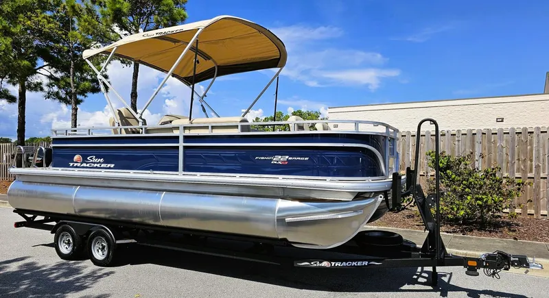 Slide: The Image of 2025 Sun Tracker Fishin' Barge 22 XP3 pontoon boat on trailer, parked outdoors. - 5