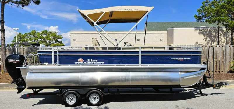 Slide: The Image of 2025 Sun Tracker Fishin' Barge 22 XP3 pontoon boat on trailer, parked outdoors. - 9