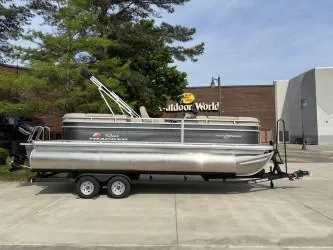 Slide: The Image of 2025 Sun Tracker Party Barge 22 RF XP3 pontoon boat on trailer, parked outdoors. - 2