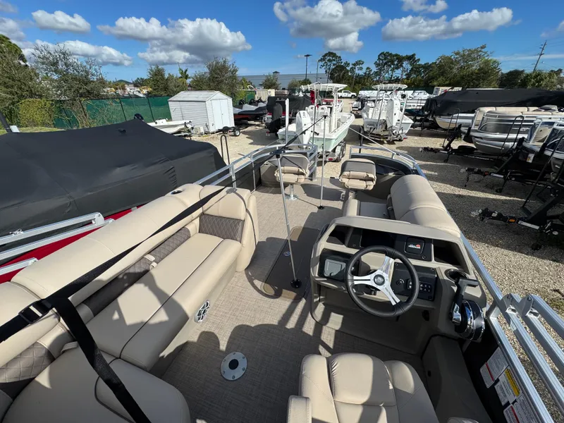 Slide: The Image of 2025 Sun Tracker Fishin' Barge 22 XP3 pontoon boat with beige seating and steering console. - 3