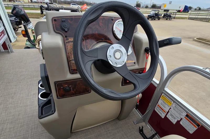 Slide: The Image of 2025 Sun Tracker Bass Buggy 18 DLX steering console with modern controls and cup holders. - 8