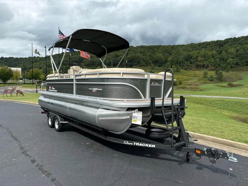 Slide: The Image of 2025 Sun Tracker Party Barge 22 RF XP3 pontoon boat on trailer, parked outdoors. - 2