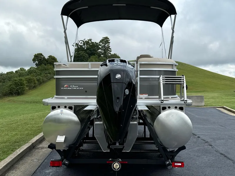 Slide: The Image of 2025 Sun Tracker Party Barge 22 RF XP3 pontoon boat with outboard motor, parked on a trailer. - 7