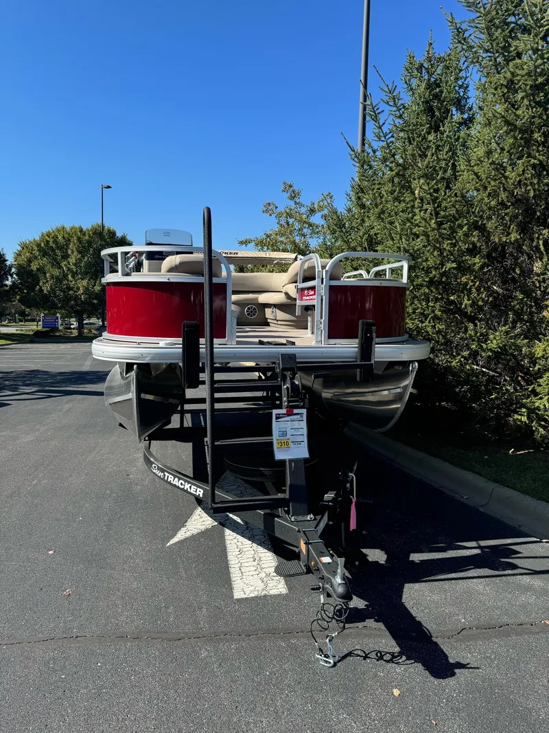 Slide: The Image of 2025 Sun Tracker Bass Buggy 18 DLX pontoon boat parked outdoors. - 2