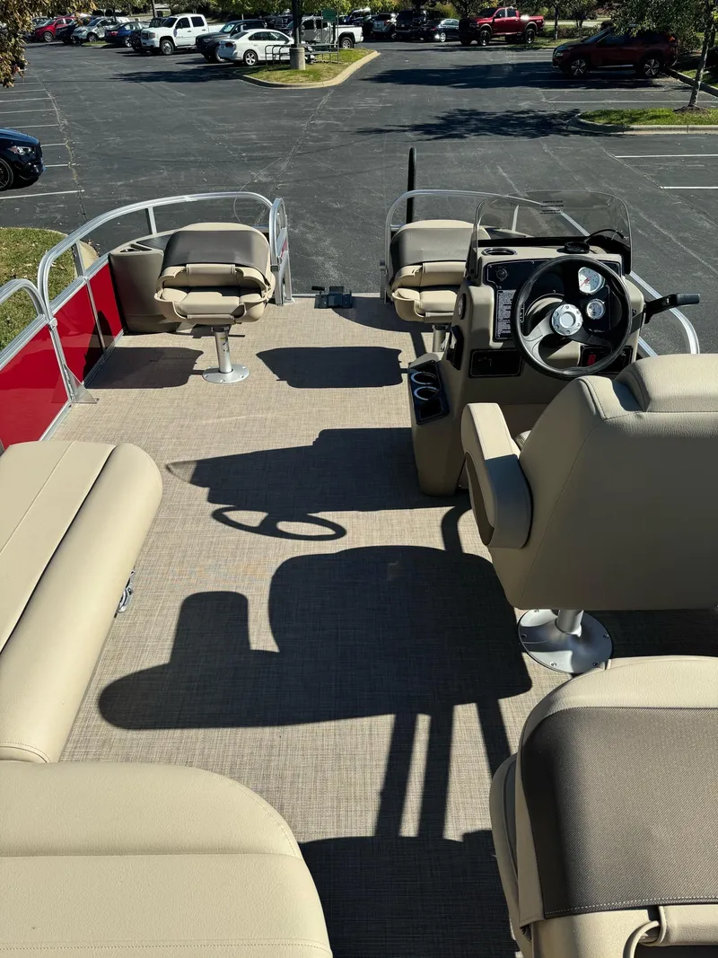 Slide: The Image of 2025 Sun Tracker Bass Buggy 18 DLX pontoon boat interior with beige seating and steering console. - 3