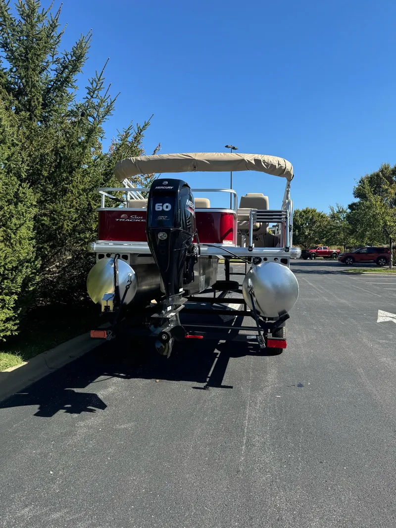 Slide: The Image of 2025 Sun Tracker Bass Buggy 18 DLX pontoon boat on trailer, parked outdoors. - 5