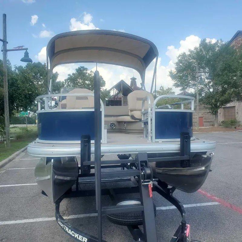 Slide: The Image of 2025 Sun Tracker Bass Buggy 16 XL Select pontoon boat on trailer in parking lot. - 6
