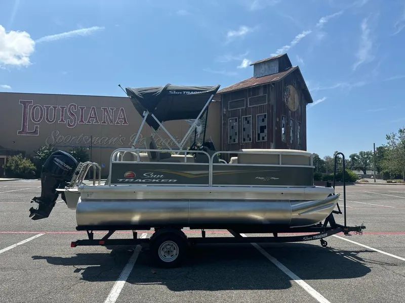 Slide: The Image of 2025 Sun Tracker Party Barge 16 DLX pontoon boat on trailer in parking lot. - 2