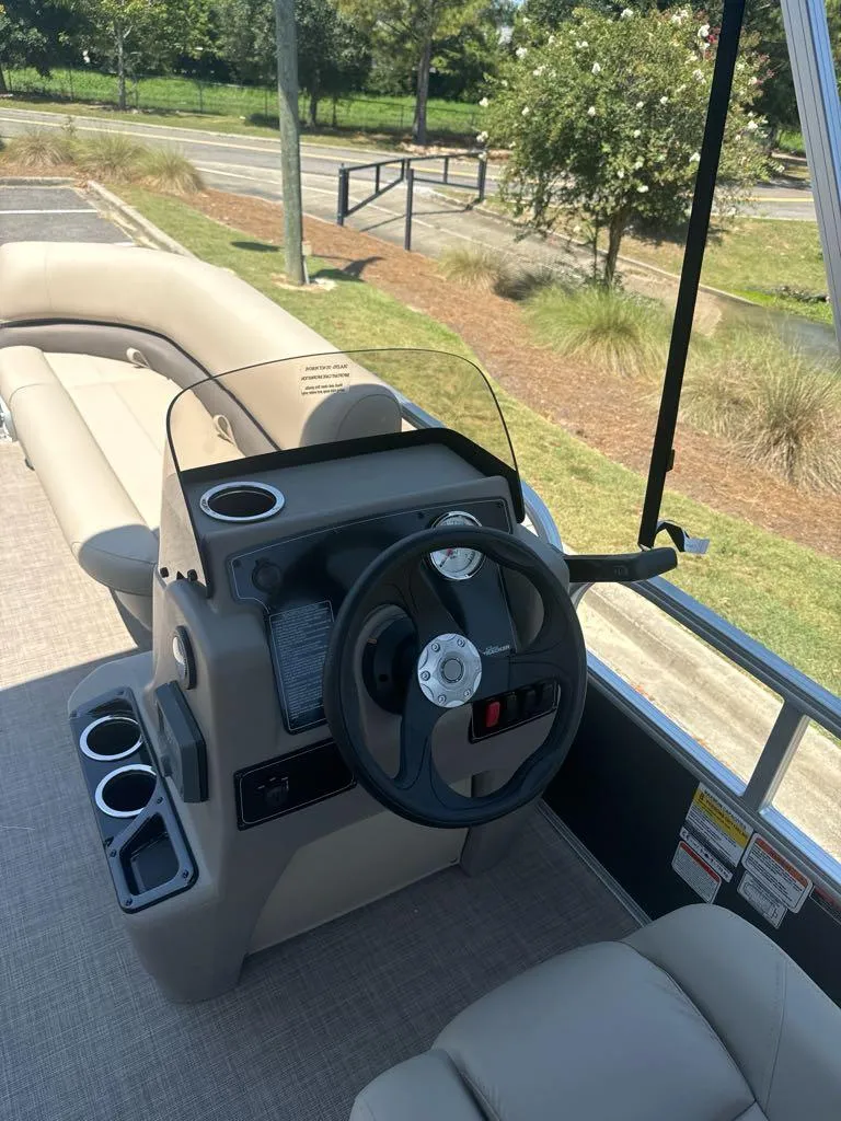 Slide: The Image of 2025 Sun Tracker Party Barge 16 DLX steering console with cup holders and seating. - 6