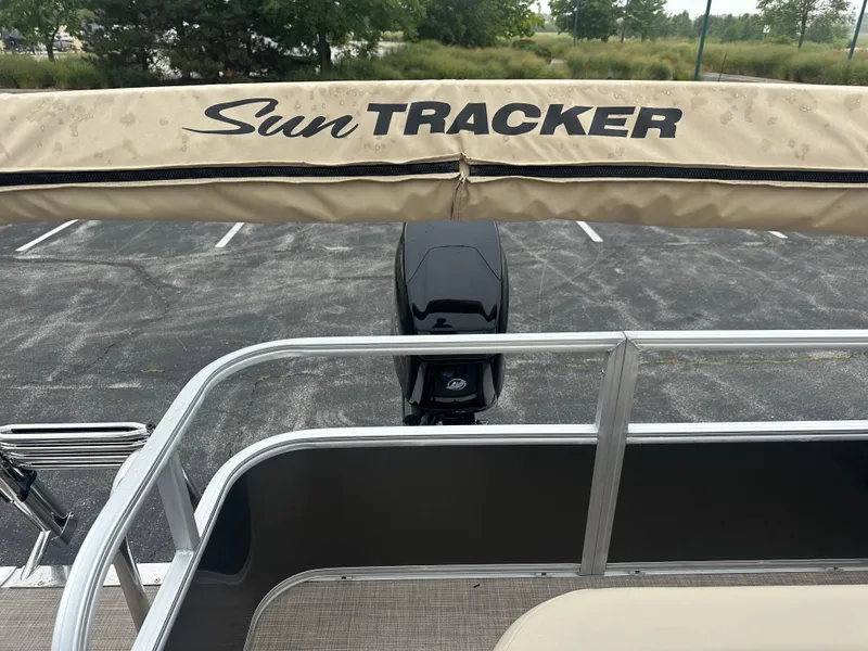 Slide: The Image of 2025 Sun Tracker Party Barge 18 DLX with canopy and motor in parking lot. - 2