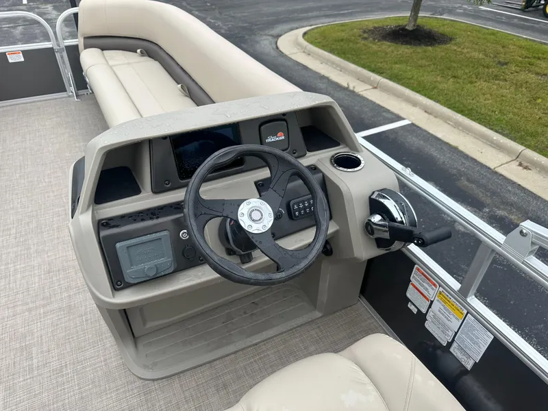 Slide: The Image of 2025 Sun Tracker Party Barge 18 DLX steering console with beige seating and controls. - 4