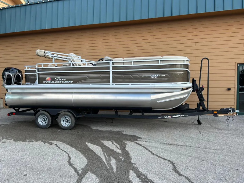 The Image of 2025 Sun Tracker SportFish 20 DLX pontoon boat on trailer, parked outdoors. - 0