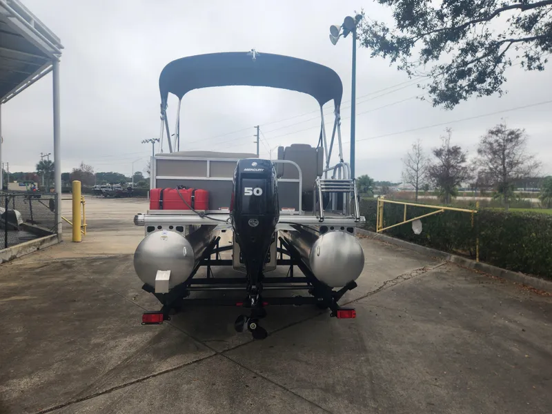 Slide: The Image of 2025 Sun Tracker Party Barge 16 DLX pontoon boat with 50 HP motor, parked outdoors. - 2