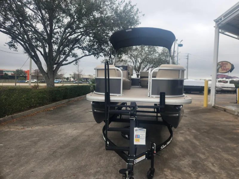 Slide: The Image of 2025 Sun Tracker Party Barge 16 DLX pontoon boat on trailer, parked outdoors. - 3