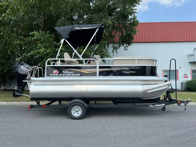 The Image of 2025 Sun Tracker Party Barge 16 DLX pontoon boat on trailer, parked outdoors. - 0
