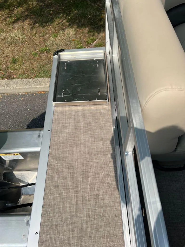 Slide: The Image of 2025 Sun Tracker Party Barge 16 DLX deck with beige seating and metal railing. - 7