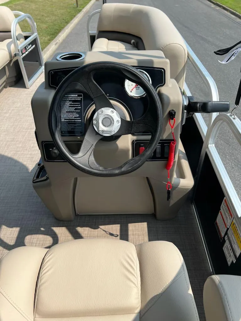 Slide: The Image of 2025 Sun Tracker Party Barge 16 DLX steering console with beige seating and controls. - 9