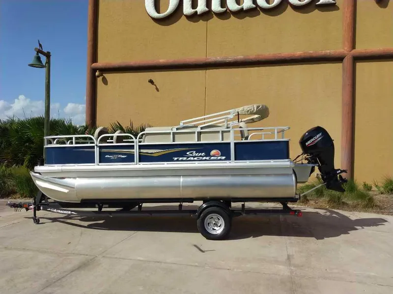 The Image of 2025 Sun Tracker Bass Buggy 18 DLX pontoon boat on trailer, outdoor setting. - 0