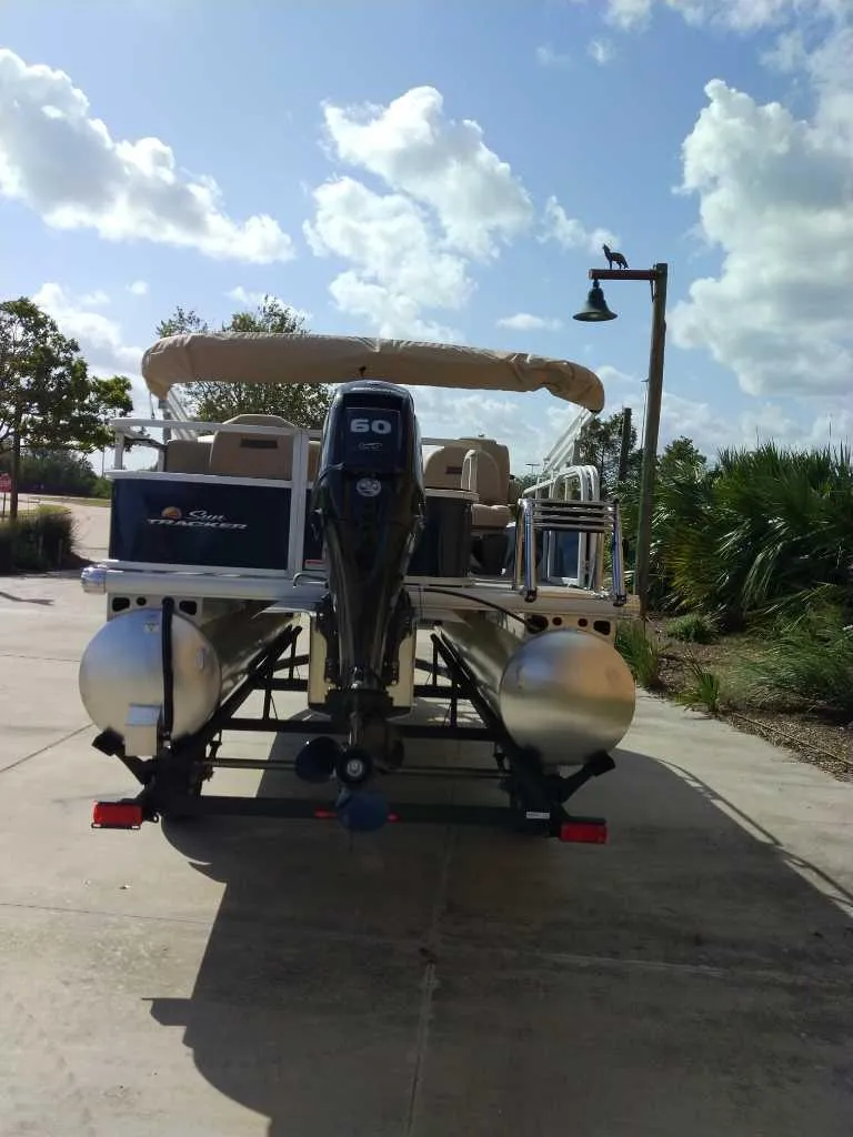 Slide: The Image of 2025 Sun Tracker Bass Buggy 18 DLX pontoon boat on trailer, parked outdoors. - 5