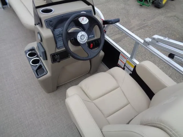 Slide: The Image of 2025 Sun Tracker Party Barge 16 DLX steering console with beige seating and cup holders. - 49