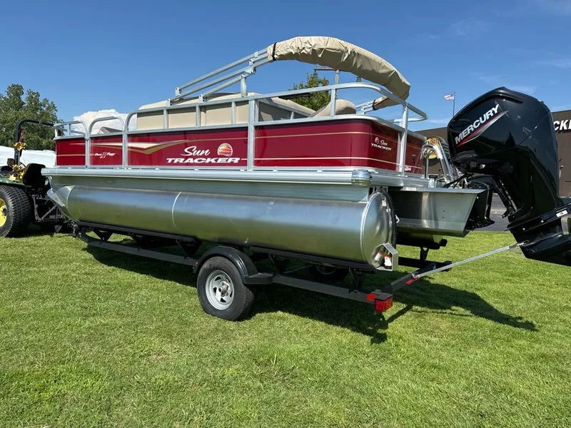 Slide: The Image of 2025 Sun Tracker Bass Buggy 18 DLX pontoon boat on trailer, grassy area. - 6