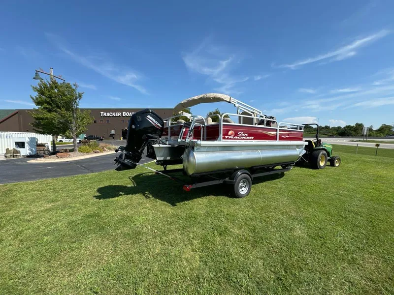 Slide: The Image of 2025 Sun Tracker Bass Buggy 18 DLX pontoon boat on trailer, parked on grass. - 9