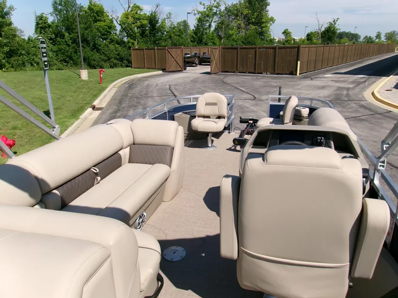 Slide: The Image of 2025 Sun Tracker Fishin' Barge 22 DLX interior with beige seating and steering console. - 5