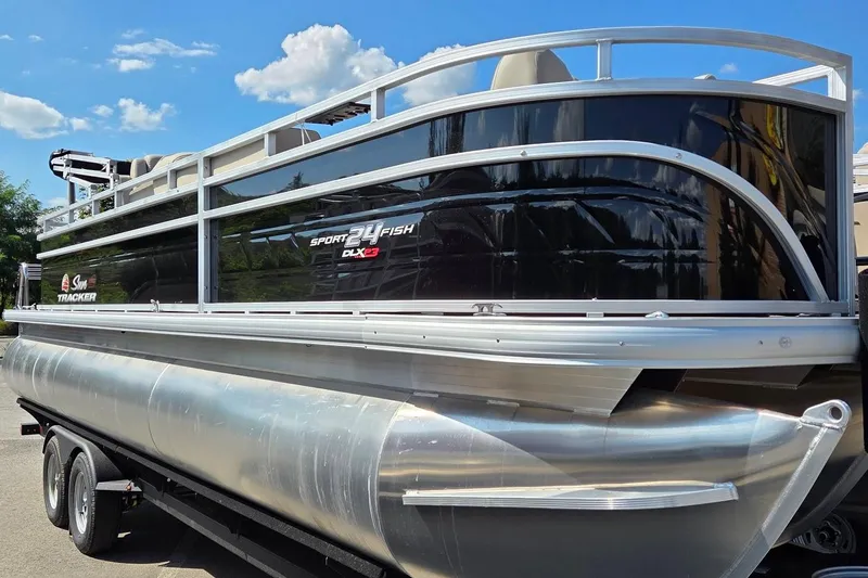 The Image of 2025 Sun Tracker Sportfish 24 XP3 pontoon boat on trailer under blue sky. - 0