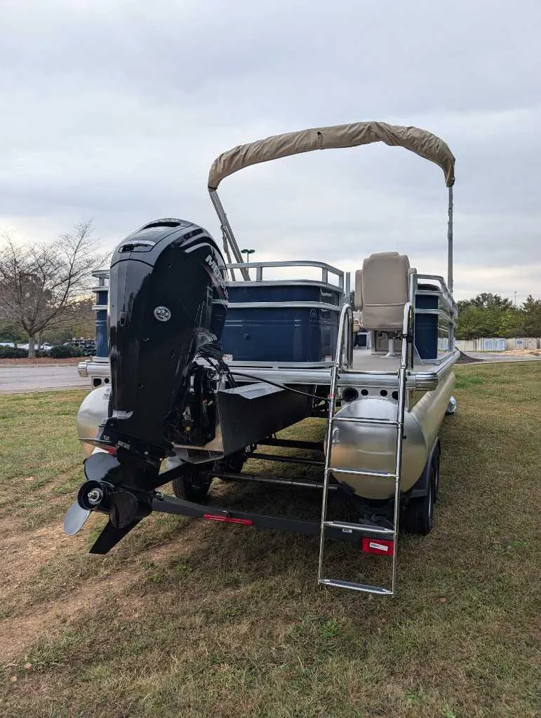 Slide: The Image of 2025 Sun Tracker Fishin' Barge 22 DLX pontoon boat with outboard motor and ladder. - 2