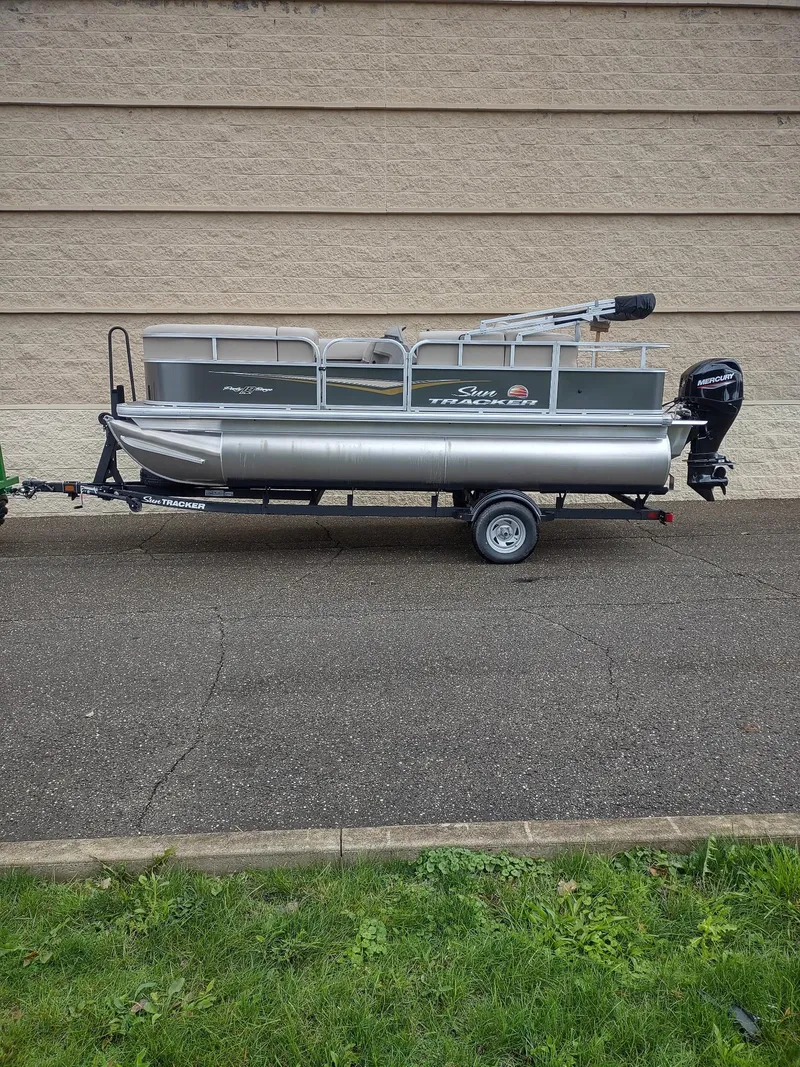 The Image of 2025 Sun Tracker Party Barge 18 DLX pontoon boat on trailer, parked outdoors. - 0