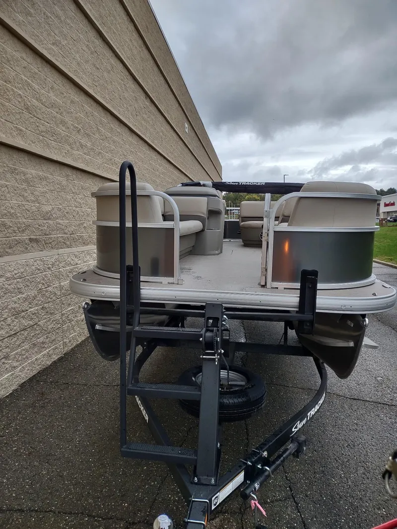 Slide: The Image of 2025 Sun Tracker Party Barge 18 DLX pontoon boat on trailer, parked outdoors. - 3