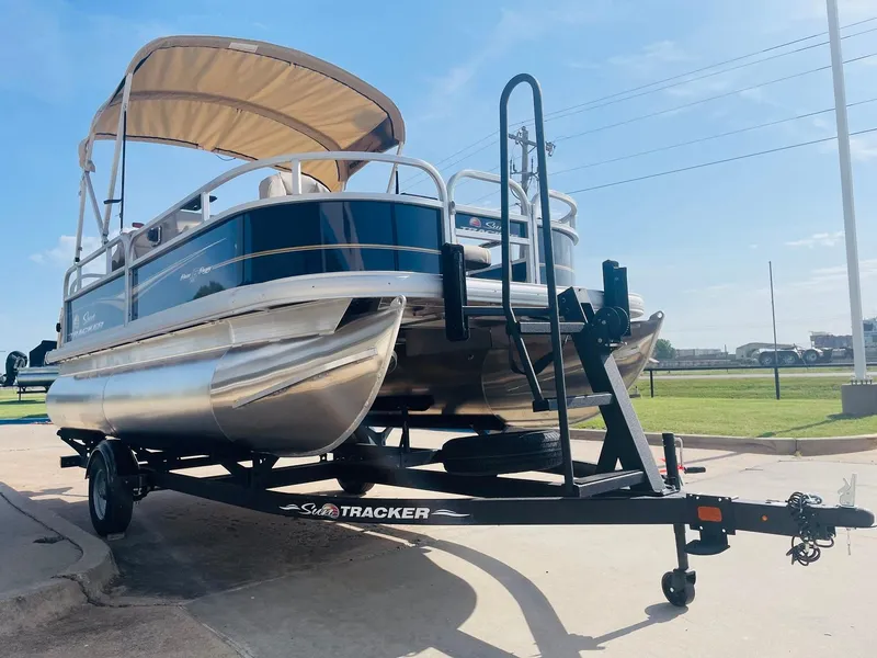 Slide: The Image of 2025 Sun Tracker Bass Buggy 16 XL Select pontoon boat on trailer, sunny day. - 3