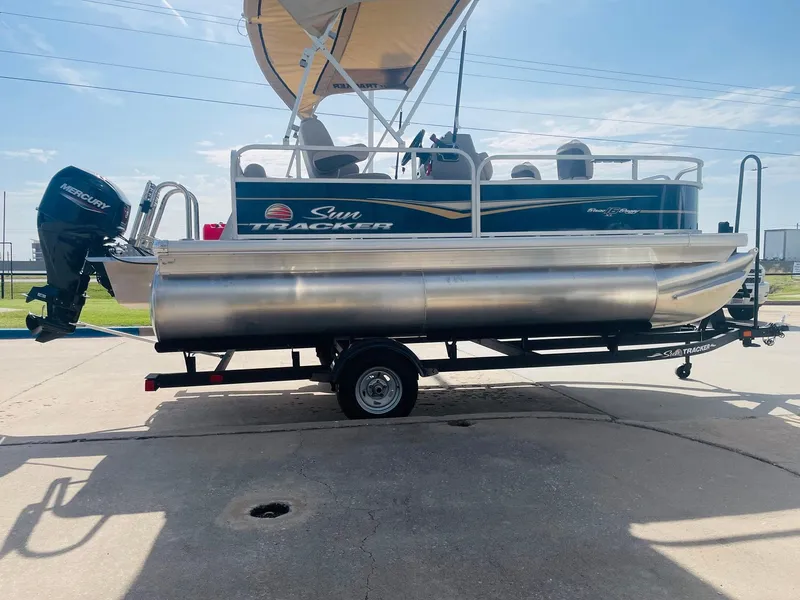 Slide: The Image of 2025 Sun Tracker Bass Buggy 16 XL Select pontoon boat on trailer, side view. - 4