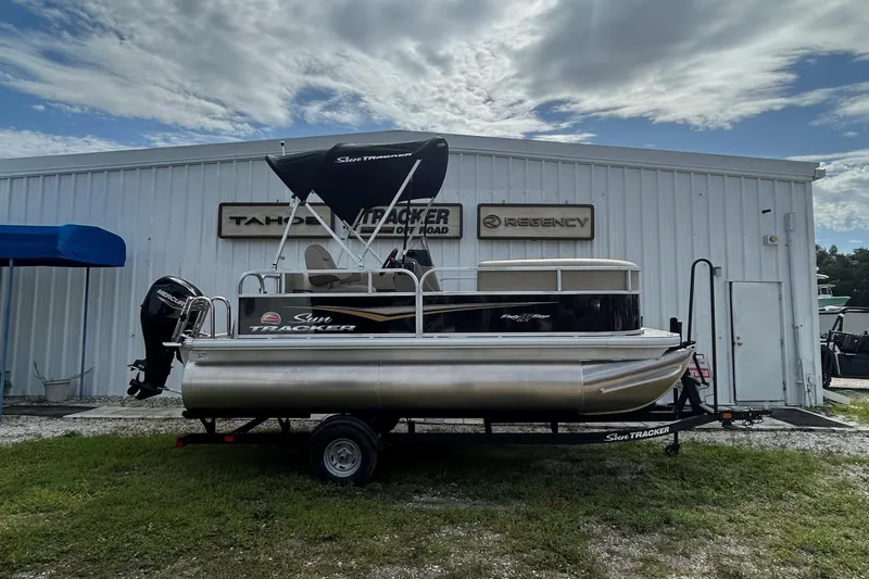 The Image of 2025 Sun Tracker Party Barge 16 DLX pontoon boat on trailer, parked outside dealership. - 0