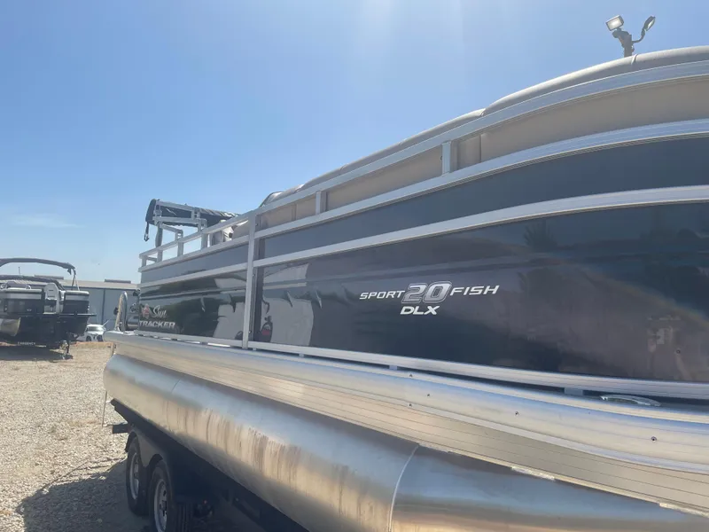 Slide: The Image of 2025 Sun Tracker SportFish 20 DLX pontoon boat under clear blue sky. - 5