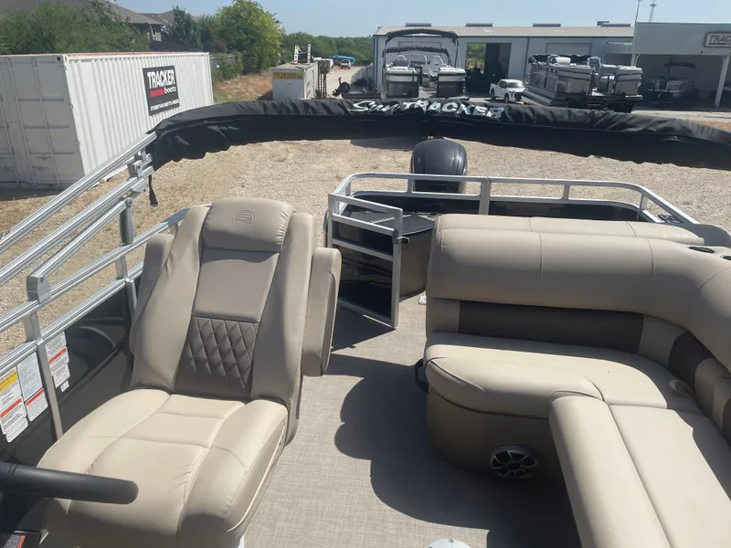 Slide: The Image of 2025 Sun Tracker SportFish 20 DLX pontoon boat interior with beige seating and steering console. - 7
