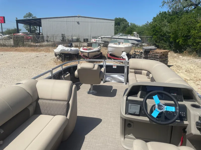 Slide: The Image of 2025 Sun Tracker SportFish 20 DLX pontoon boat with beige seating, parked outdoors. - 9