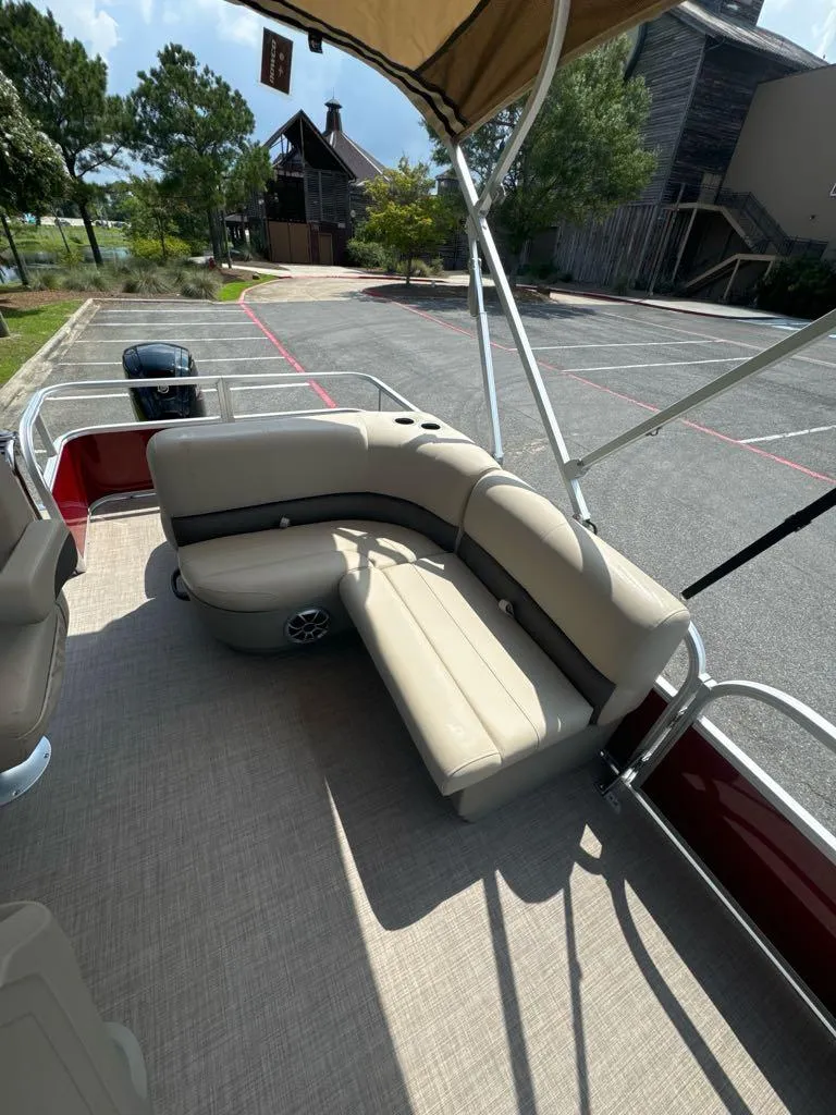 Slide: The Image of 2025 Sun Tracker Party Barge 18 DLX with beige seating and canopy in a parking lot. - 5