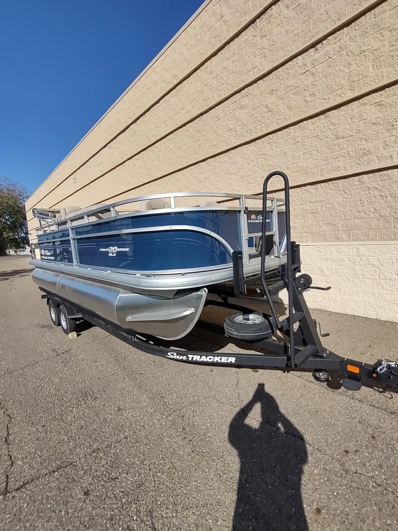 Slide: The Image of 2025 Sun Tracker Fishin' Barge 20 DLX pontoon boat on trailer, parked outdoors. - 3