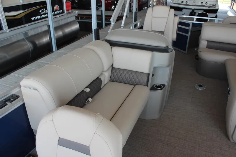 Slide: The Image of 2025 Sun Tracker Fishin' Barge 20 DLX interior with beige seating and cup holders. - 13