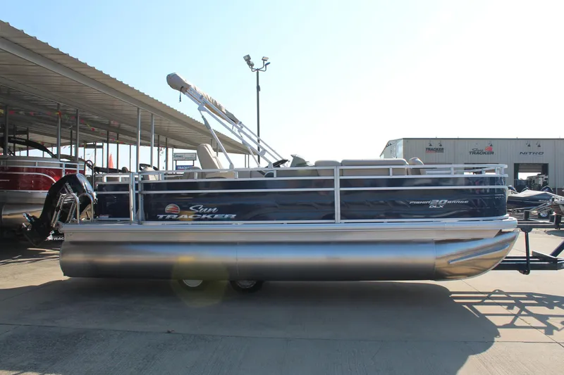 Slide: The Image of 2025 Sun Tracker Fishin' Barge 20 DLX pontoon boat docked outdoors. - 4