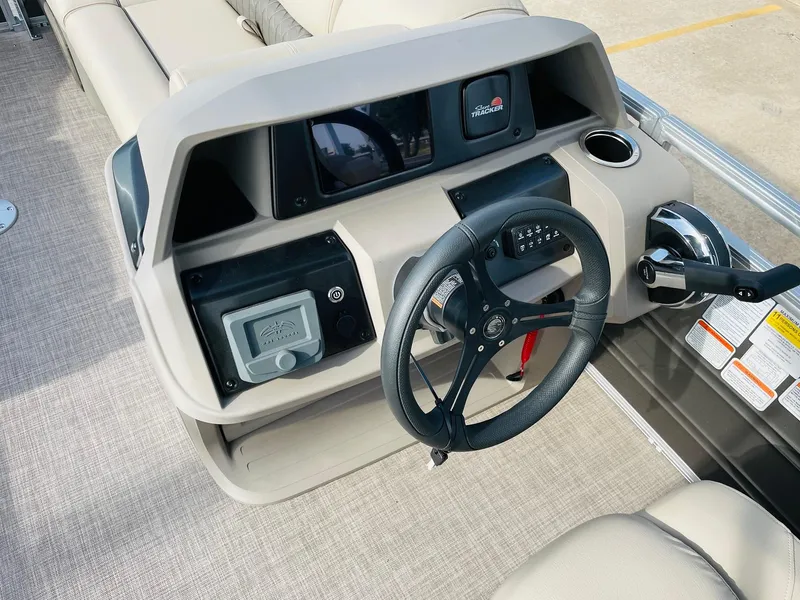 Slide: The Image of 2025 Sun Tracker Party Barge 22 RF DLX steering console with modern controls and beige upholstery. - 25