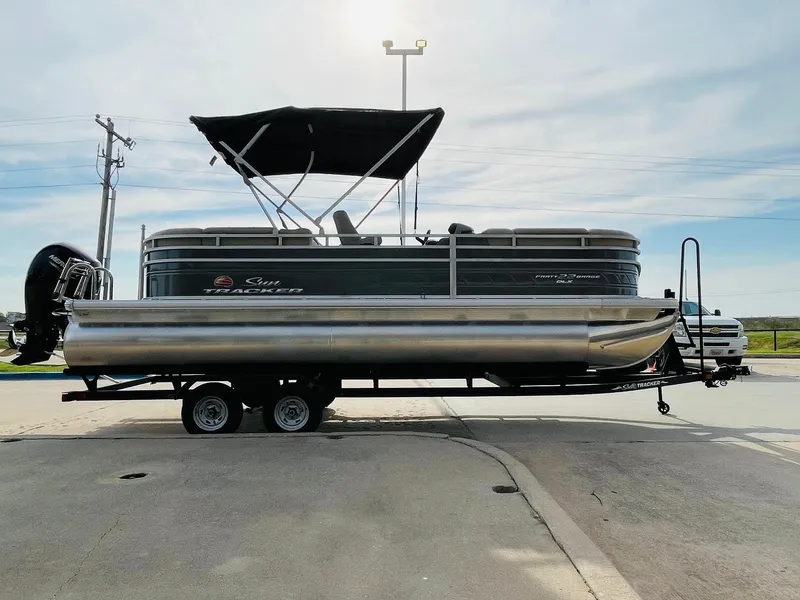 Slide: The Image of 2025 Sun Tracker Party Barge 22 RF DLX pontoon boat on trailer, side view. - 4