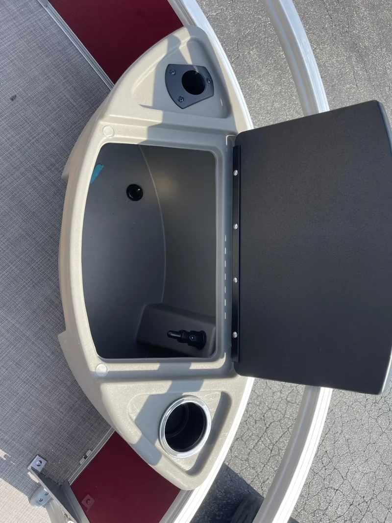 Slide: The Image of 2025 Sun Tracker Bass Buggy 18 DLX storage compartment with cup holder and open lid. - 12