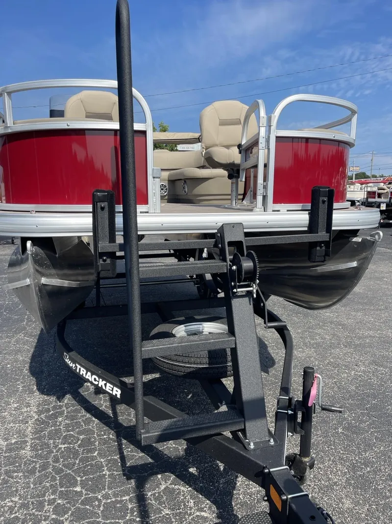 Slide: The Image of 2025 Sun Tracker Bass Buggy 18 DLX pontoon boat on trailer, red exterior, beige seating. - 2