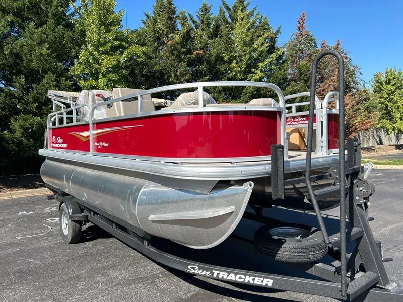The Image of 2025 Sun Tracker Bass Buggy 18 DLX pontoon boat on trailer, parked outdoors. - 0