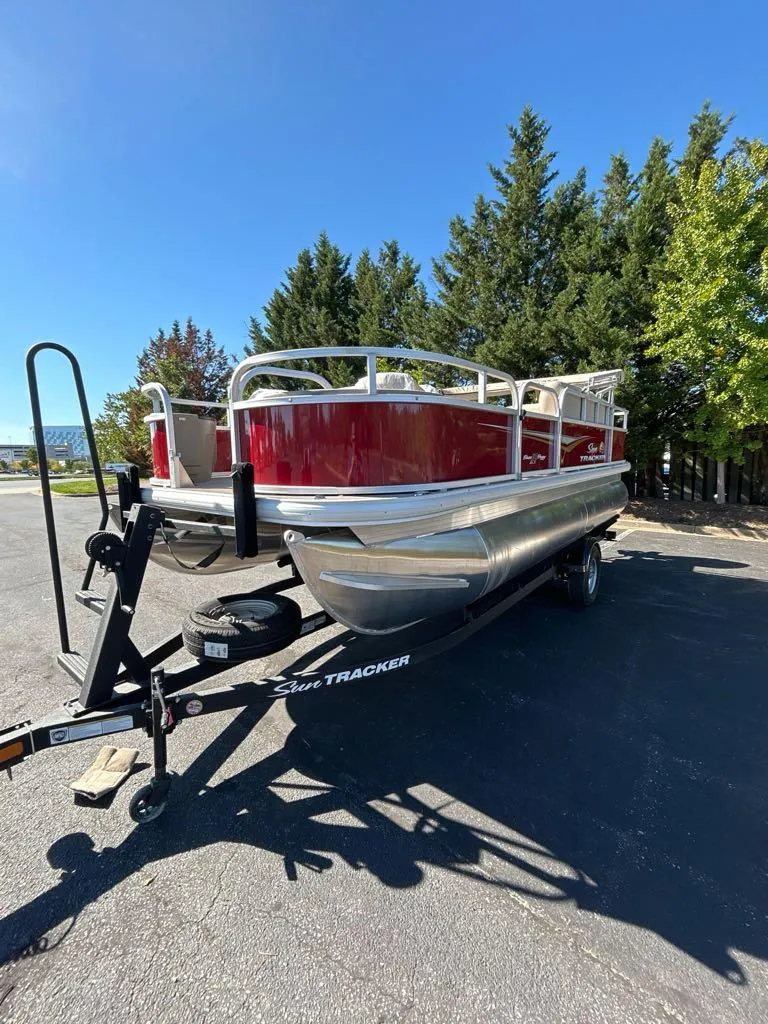 Slide: The Image of 2025 Sun Tracker Bass Buggy 18 DLX pontoon boat on trailer, parked outdoors. - 3