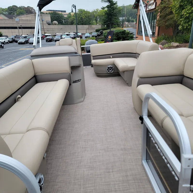 Slide: The Image of 2025 Sun Tracker Party Barge 18 DLX with beige seating, parked outdoors. - 2