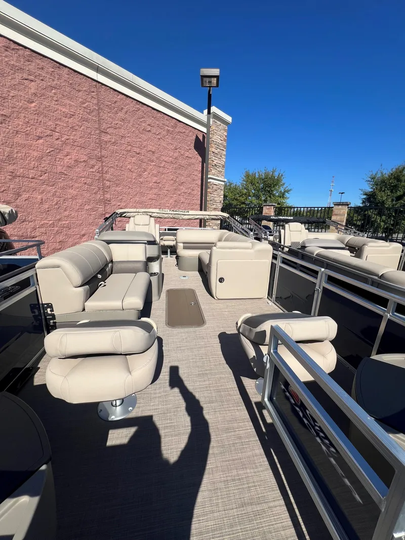 Slide: The Image of 2025 Sun Tracker Fishin' Barge 22 XP3 pontoon boat with beige seating and spacious deck. - 2